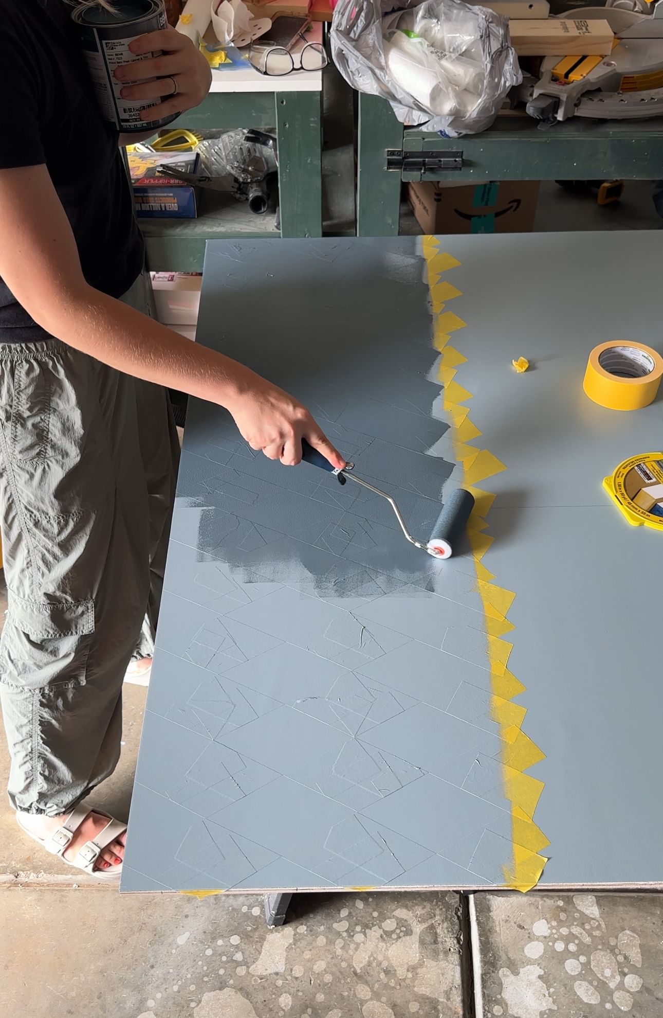 blue paint being applied with a roller to a piece of drywall