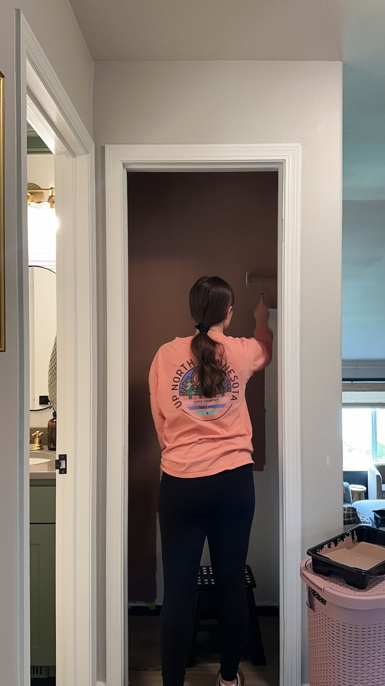 A woman painting the inside of a closet with a paint roller