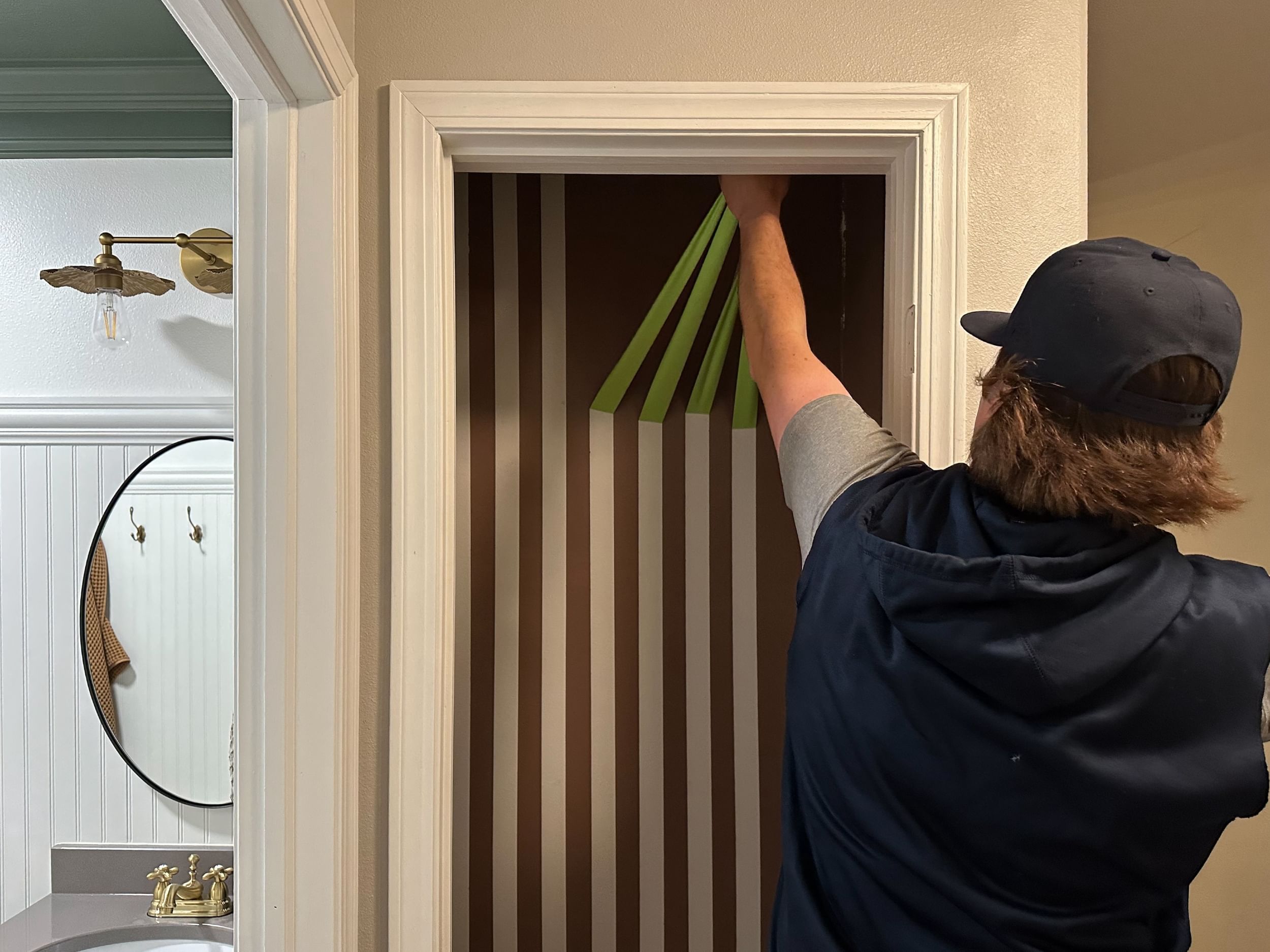 Green FrogTape Advanced strips being pulled off of a freshly painted closet wall to reveal crisp paint lines