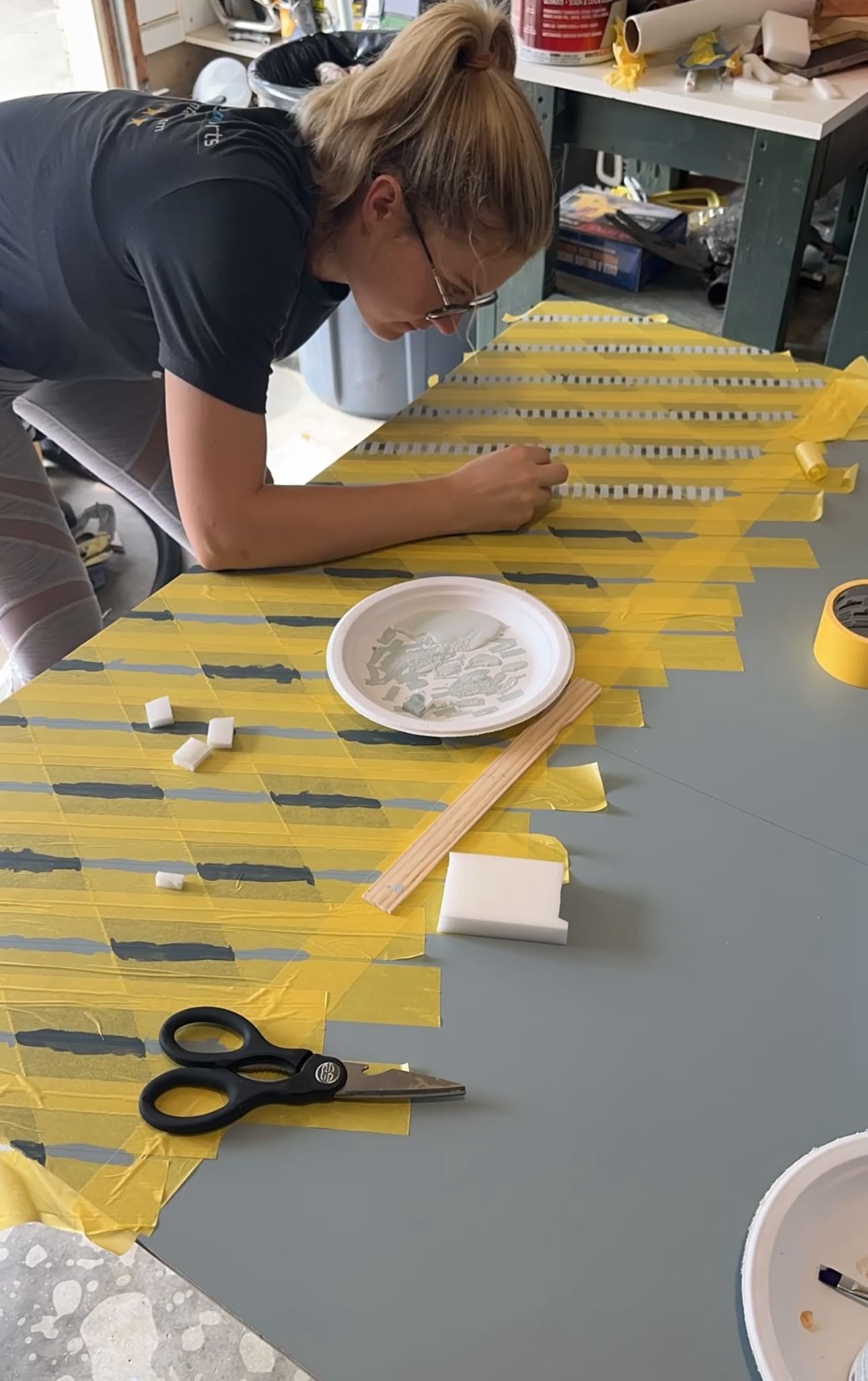 Woman adding patterned lines to a piece of painted drywall