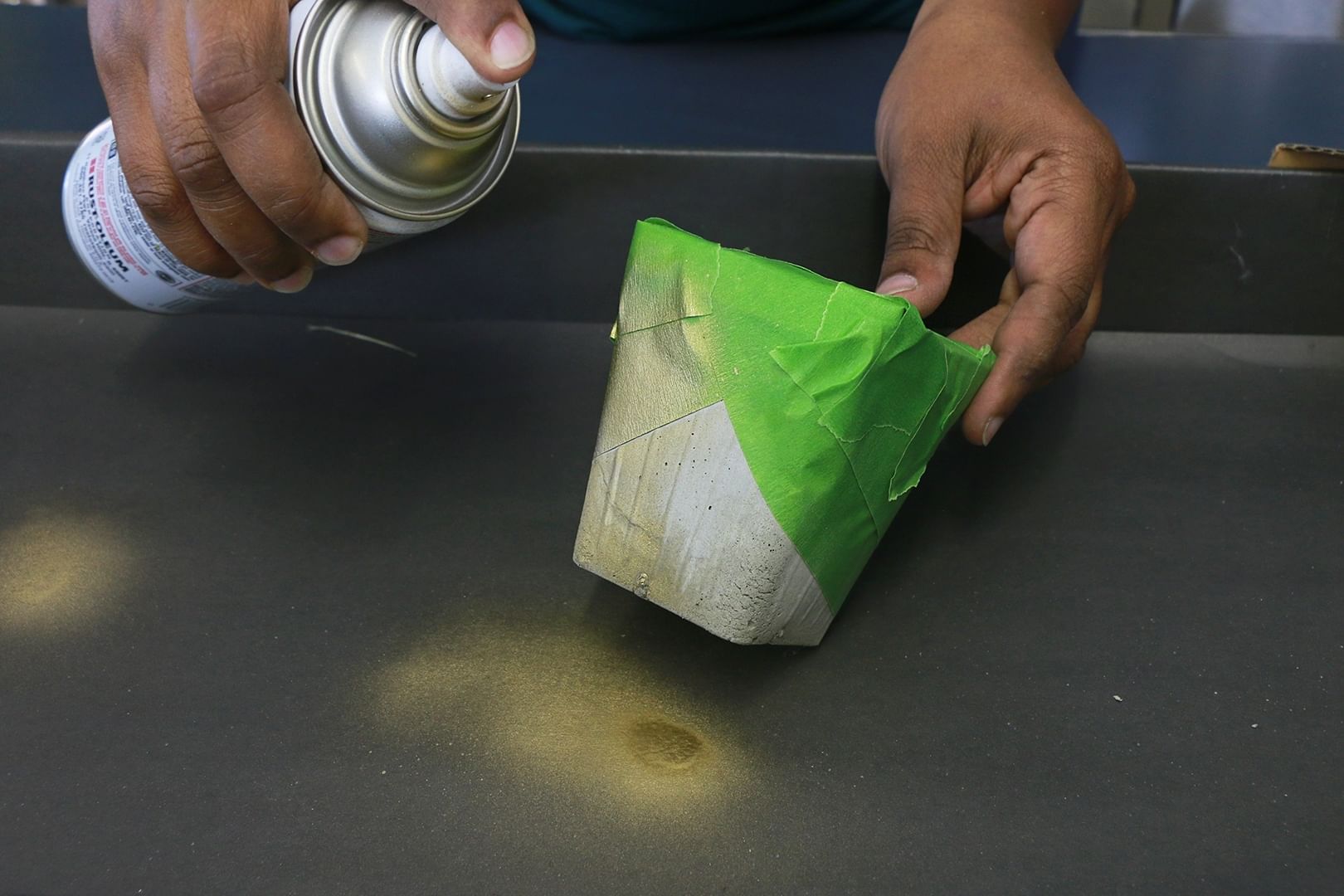 Close up shot of someone spray painting planters with tape diagonally placed