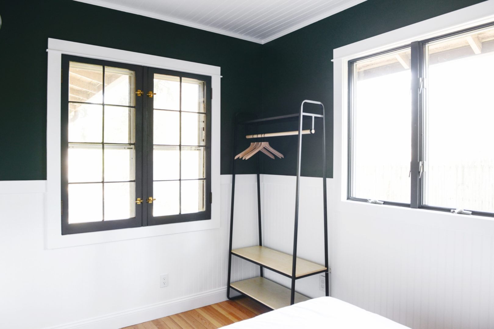 Room with large windows. The lower half of the walls in the room are white and the upper half are black.