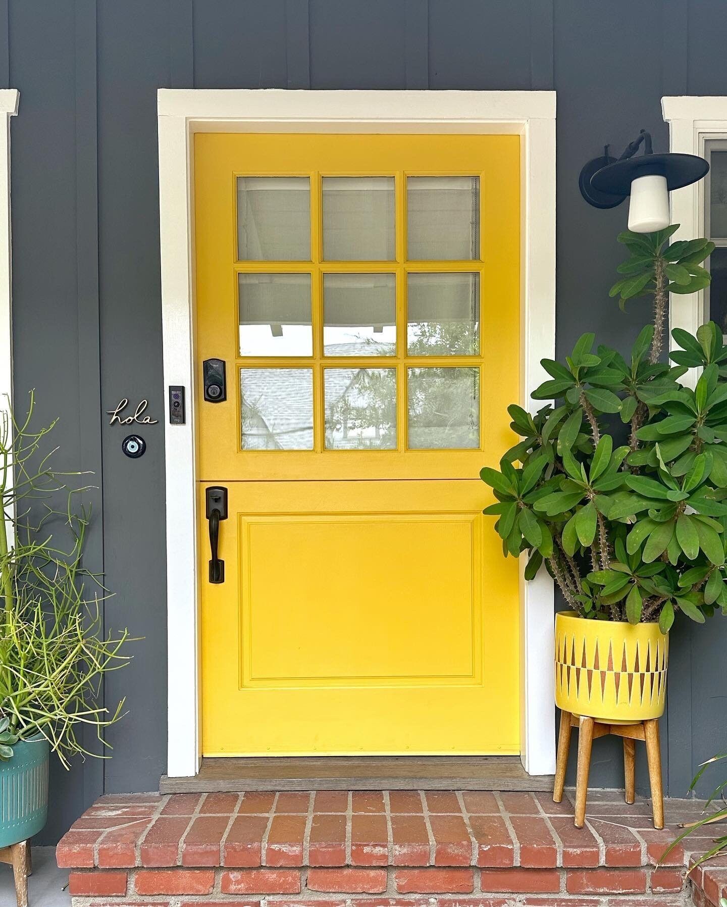 Birght yellow exterior door with white trim and charcoal house exterior