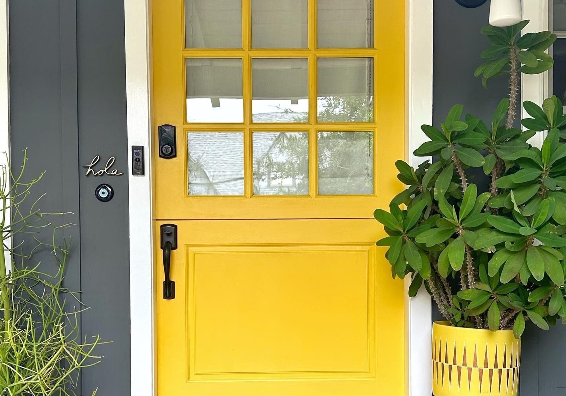 Birght yellow exterior door with white trim and charcoal house exterior