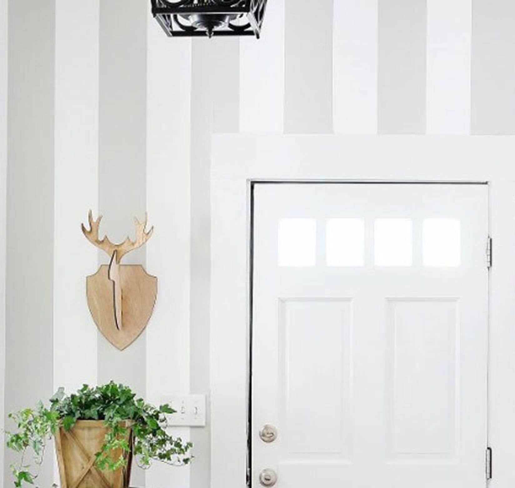 Gray and white vertical striped entryway with white door.