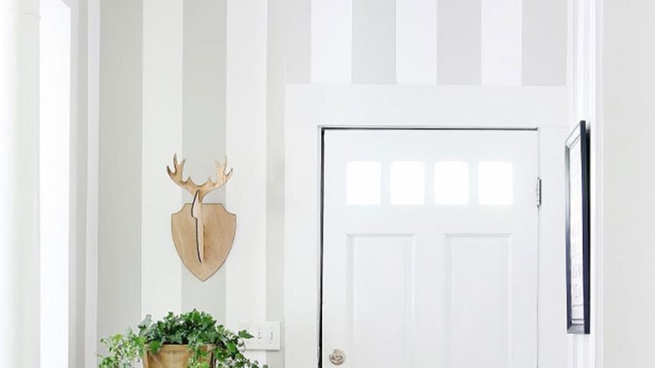 Gray and white vertical striped entryway with white door.