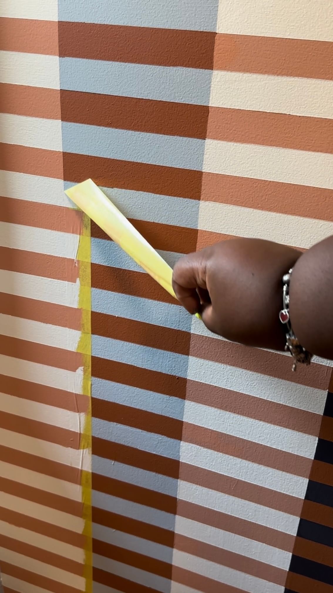 Sarah Nelson removing Yellow FrogTape Delicate Surface Painter's Tape from the wall.