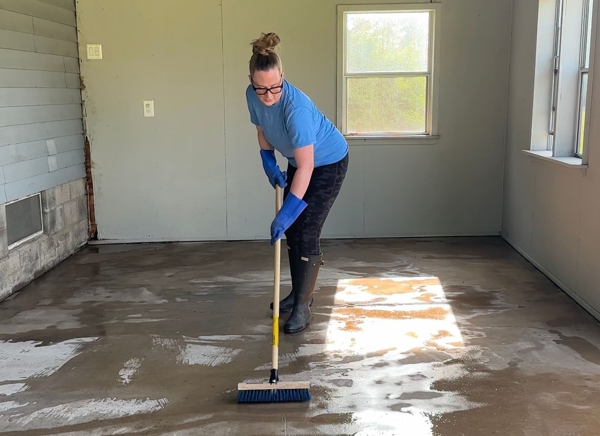 Woman cleaning patio floor with push broom
