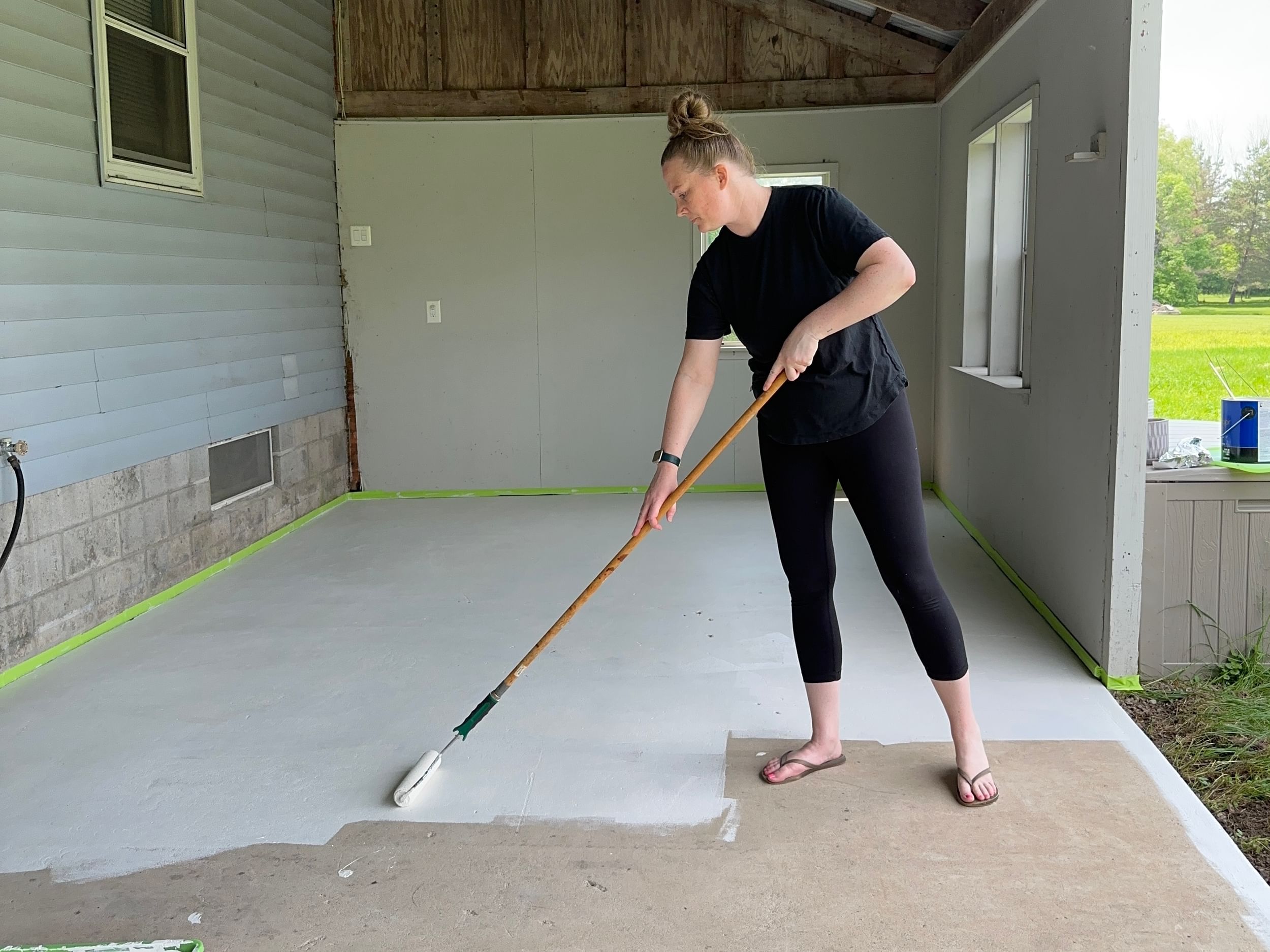 Woman painting her patio floor with a roller