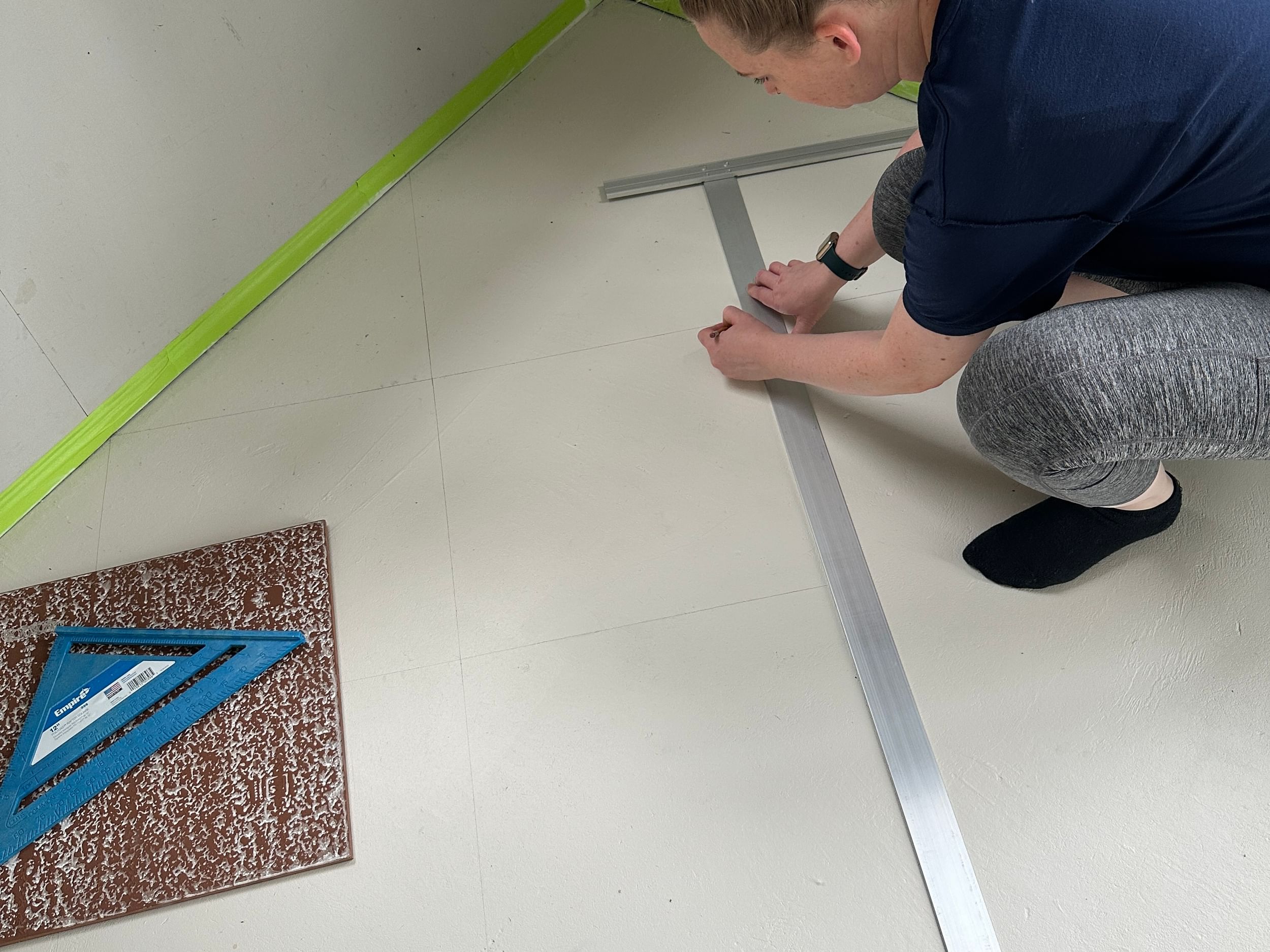 Woman using a straight edge to mark even squares on her patio floor