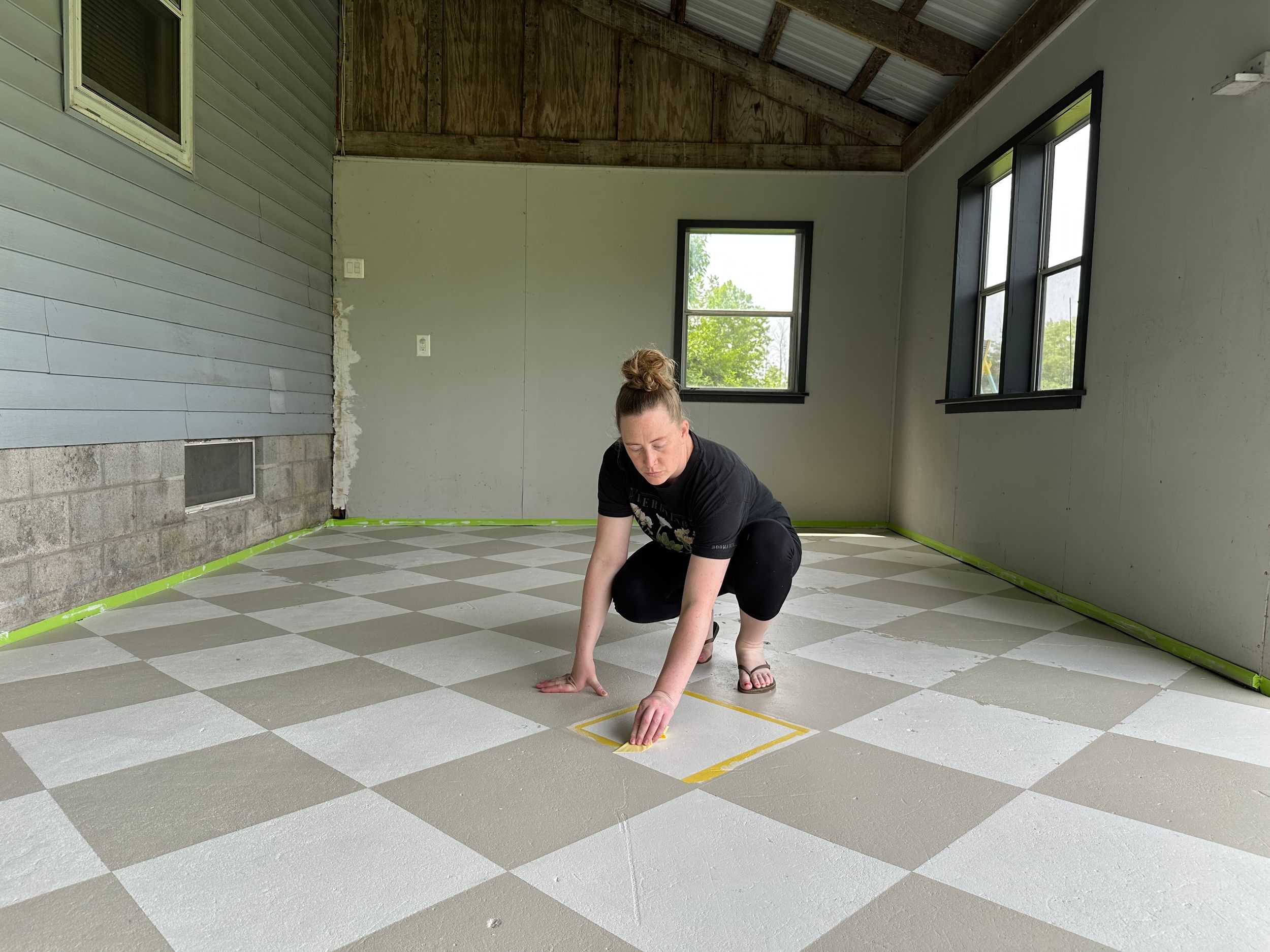 Woman Peeling off FrogTape Delicate Surface Painter's Tape from her patio floor to reveal a crisp checkerboard pattern